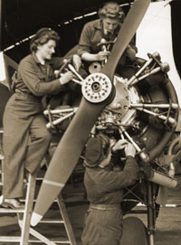Photo: WAAF mechanics working on the engine of a propeller driven aircraft.